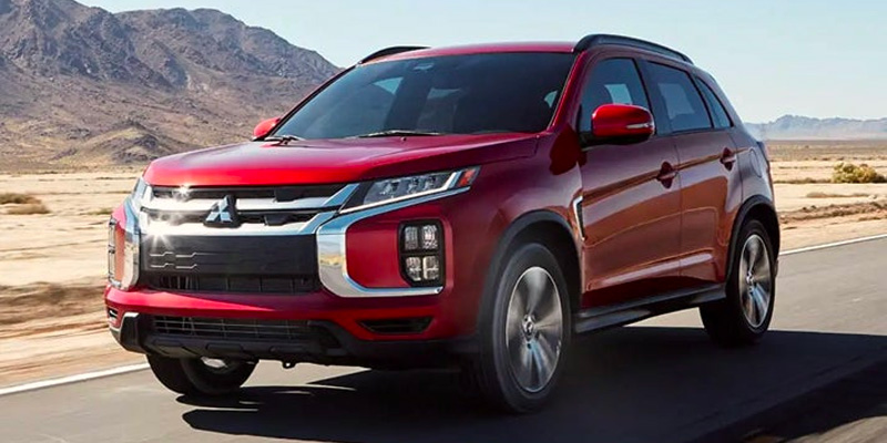 A red 2025 Mitsubishi Outlander Sport driving on a road