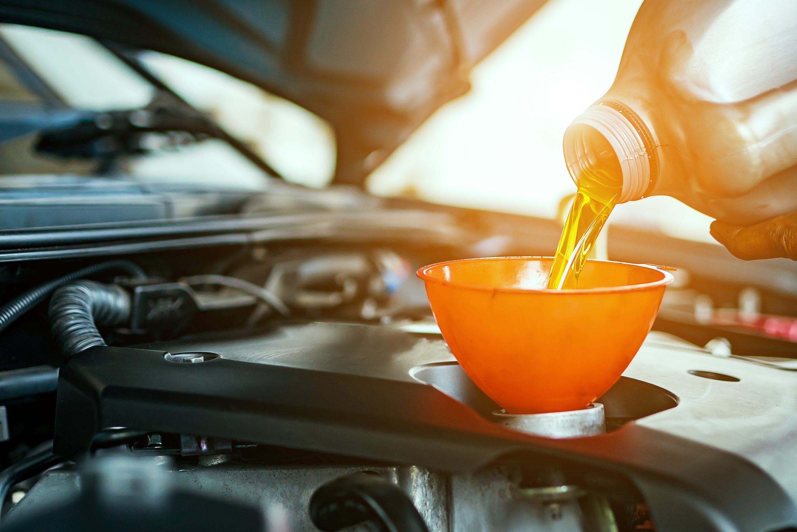 an image of motor oil being poured into a funnel on a cars engine